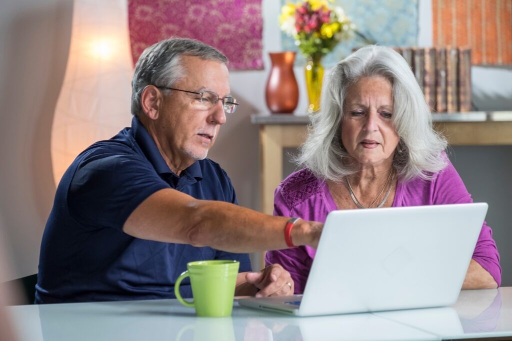 A senior aged couple looking at their bills online