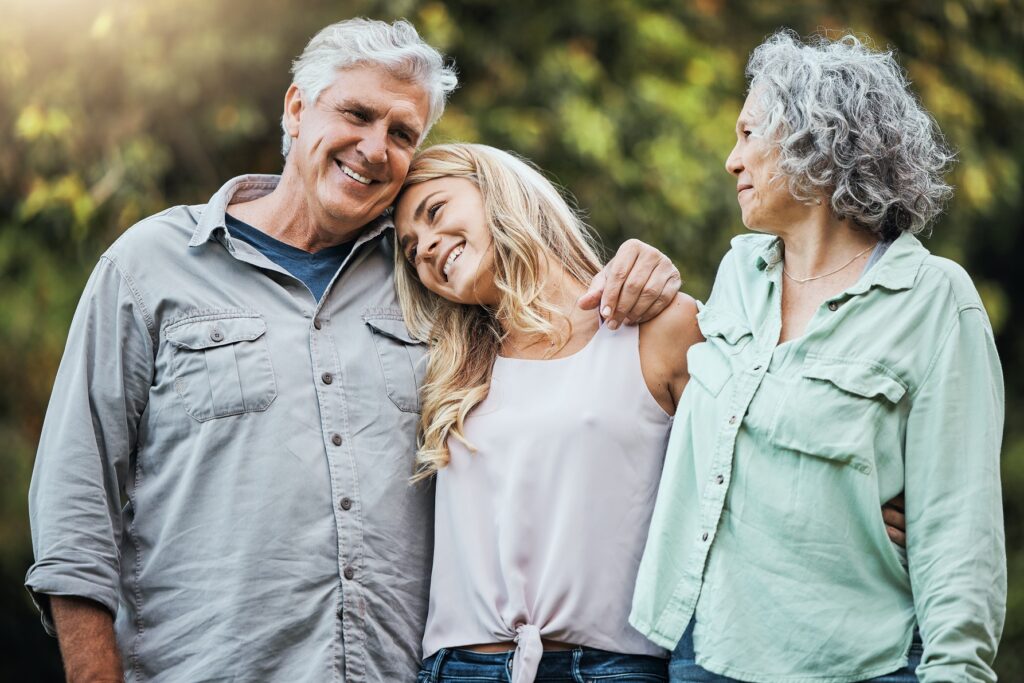 Nature, senior parents and hug with daughter to bond on weekend in usa for happy family moment. Proud, elderly and retirement people with woman relatives smile together with care and love embrace